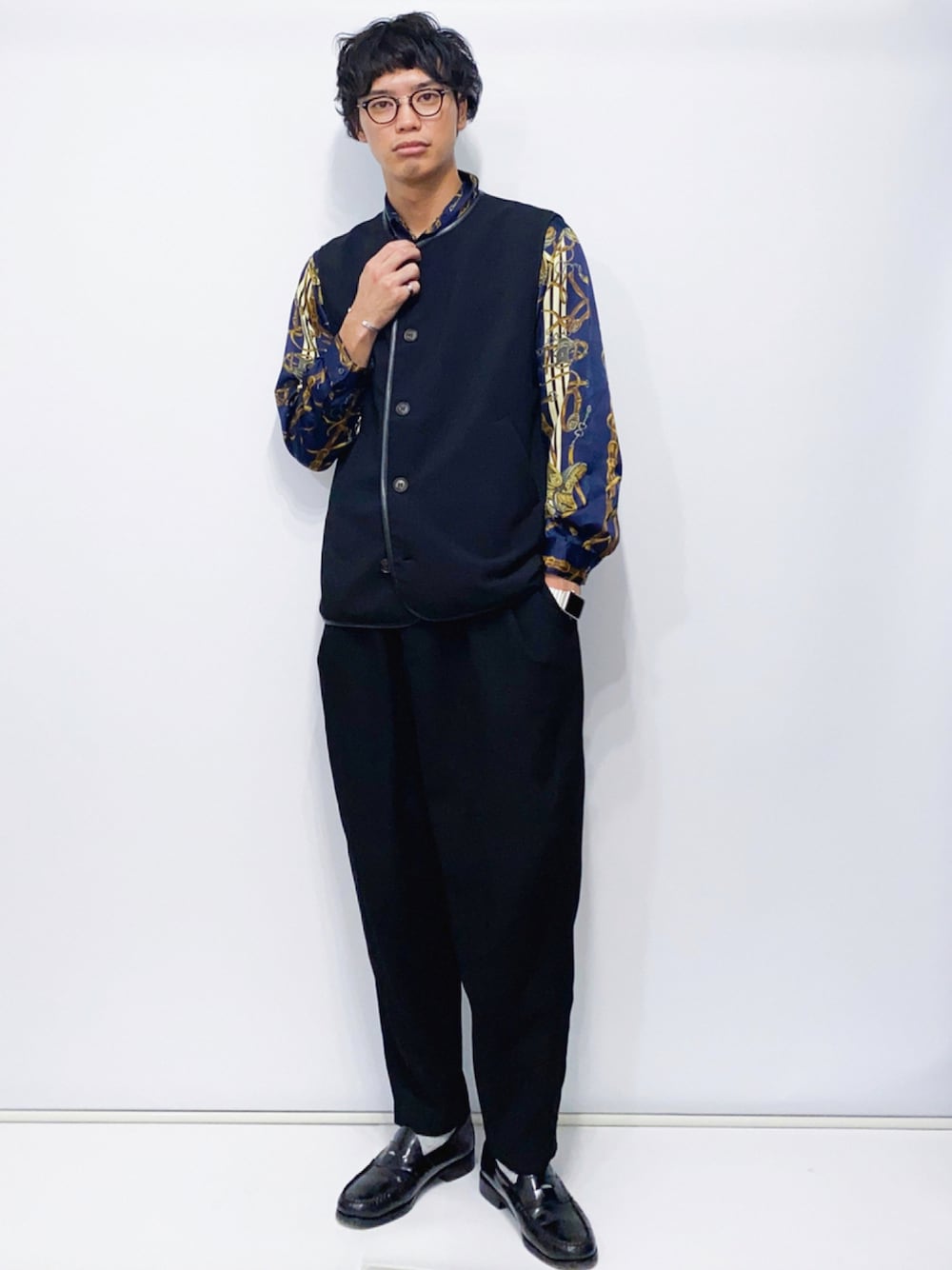 ブラック系のベスト、ブラック系のスラックス、ブラック系のローファーを着用したメンズの秋コーディネートの1枚目の写真