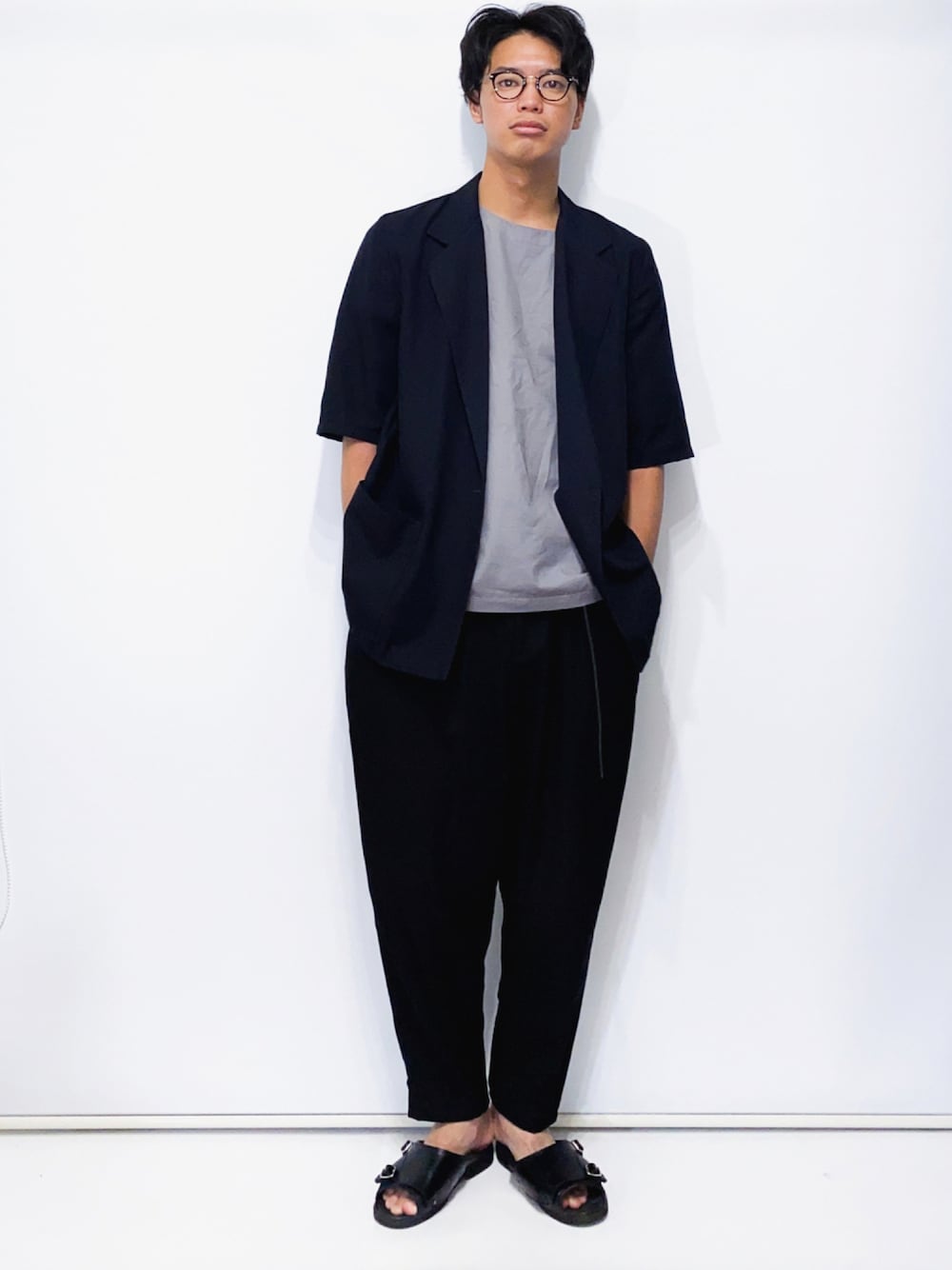 ブラック系のテーラードジャケット、グレー系のTシャツ/カットソー、ブラック系のスラックスを着用したメンズの夏コーディネートの1枚目の写真