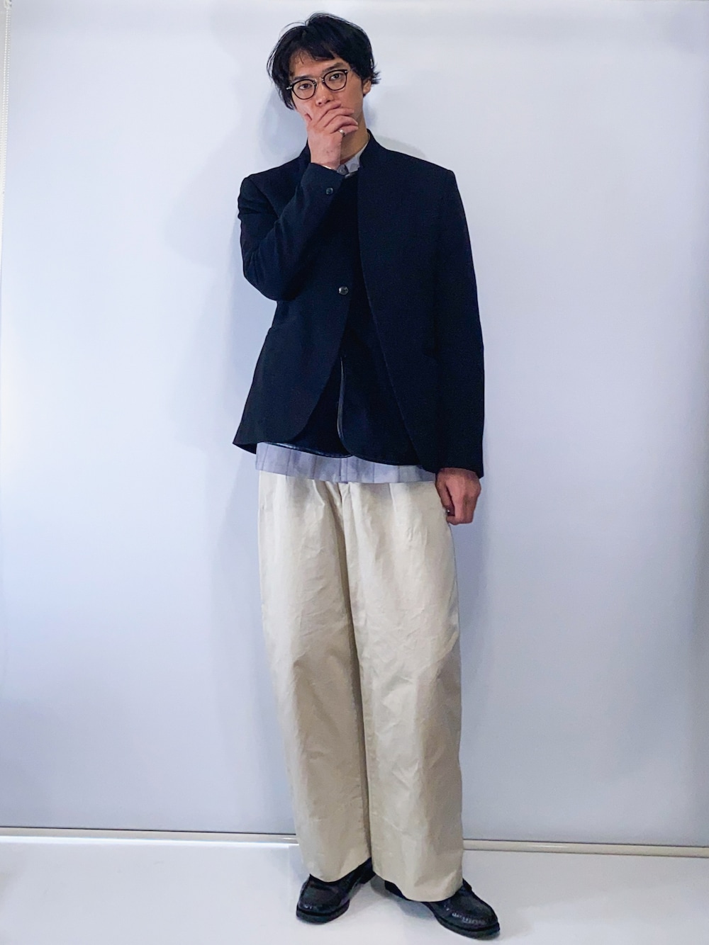 ブラック系のテーラードジャケット、ブラック系のベスト、ベージュ系のパンツを着用したメンズの冬コーディネートの1枚目の写真