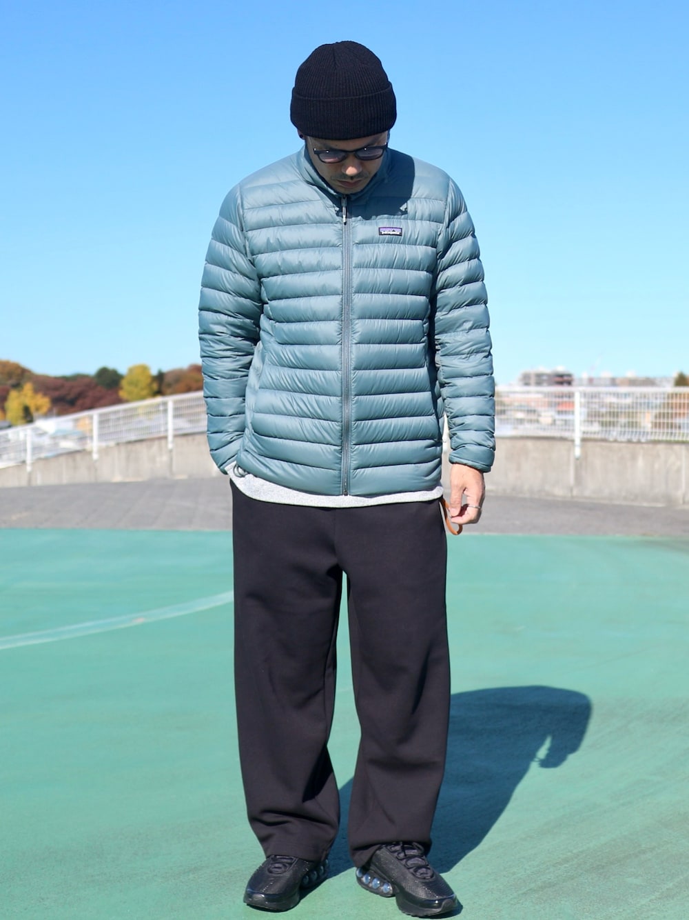 ブラック系のスニーカー、グレー系のTシャツ/カットソー、ブルー系のダウンジャケット/コートを着用したメンズの秋コーディネートの1枚目の写真