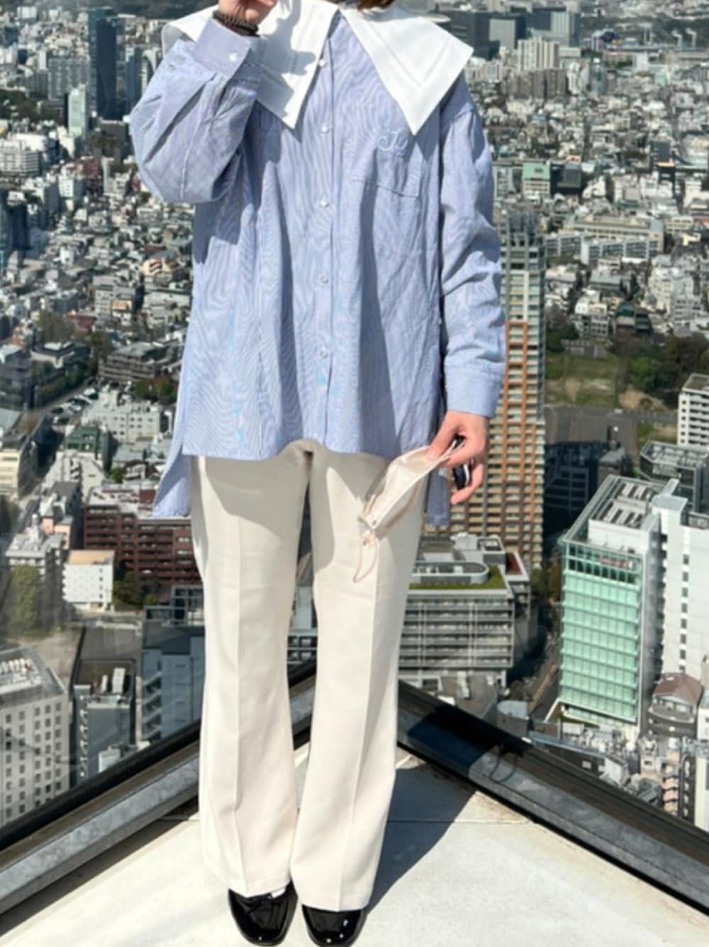 ブルー系のシャツ/ブラウス、ブラック系のレインシューズ、ホワイト系のスラックスを着用したレディースの春コーディネートの1枚目の写真