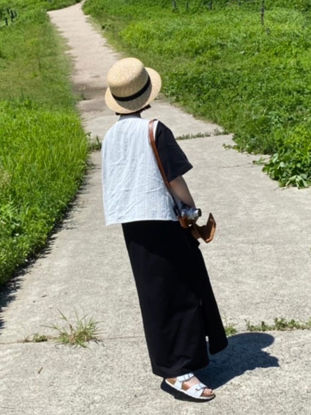 ホワイト系のベスト、ブラック系のワンピース/ドレス、ホワイト系のサンダルを着用したレディースの夏コーディネートの1枚目の写真