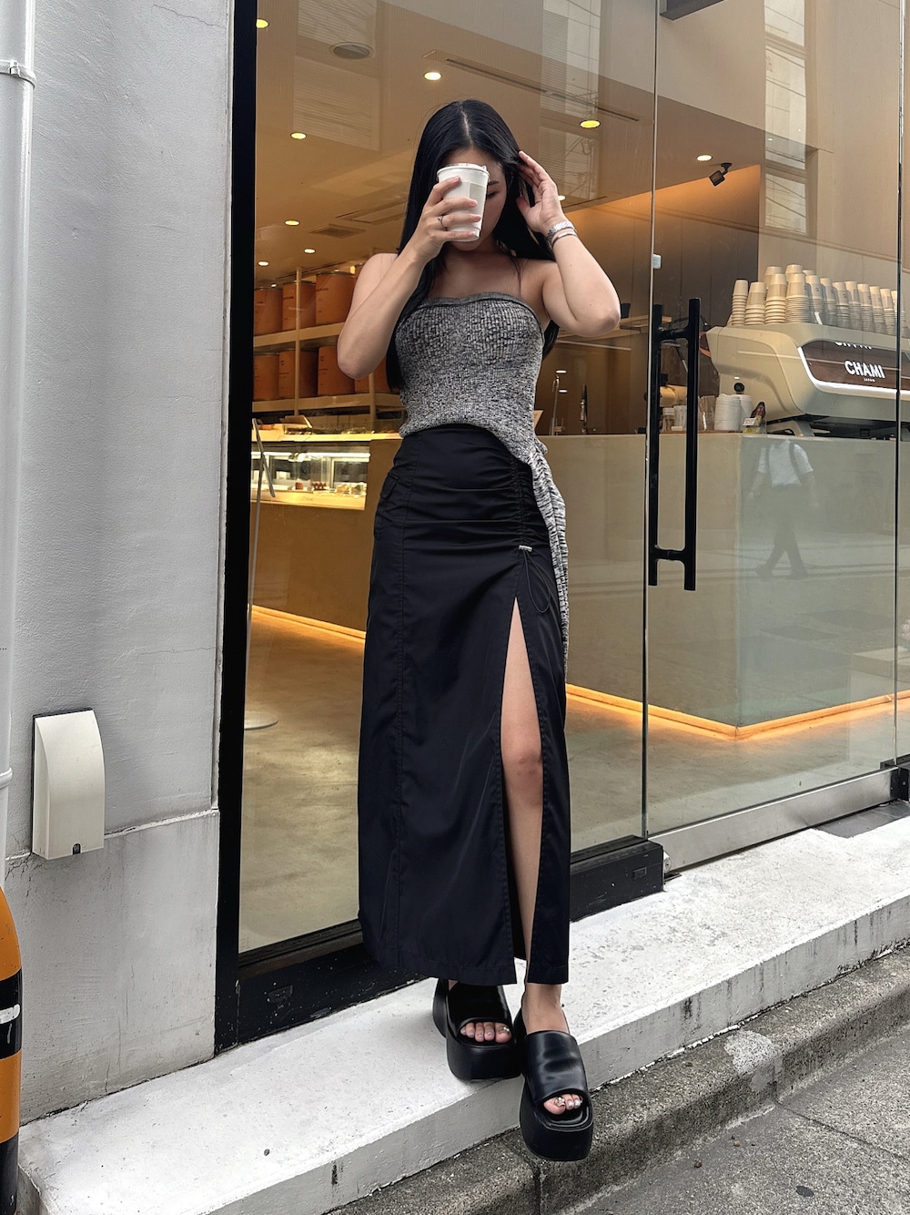 グレー系のトップス、ブラック系のスカート、ブラック系のサンダルを着用したレディースの秋コーディネートの1枚目の写真