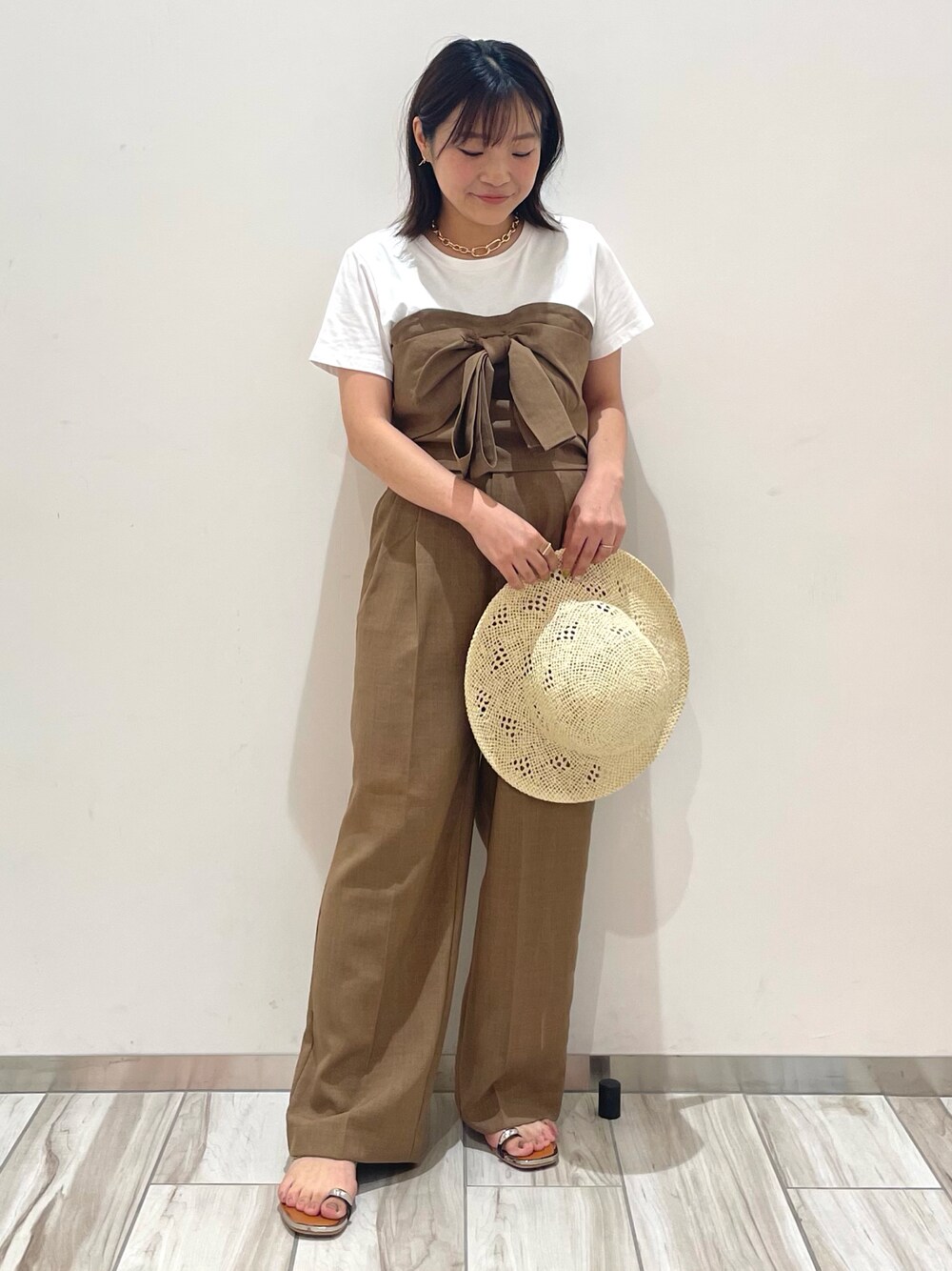 ブラウン系のスラックスを着用したレディースの夏コーディネートの1枚目の写真
