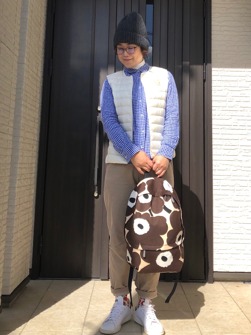 ブラウン系のバックパック/リュック、ホワイト系のスニーカー、ホワイト系のダウンベストを着用したレディースの秋コーディネートの1枚目の写真