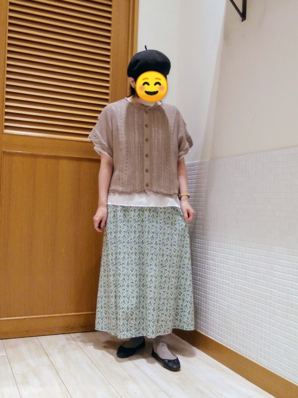 ブラウン系のベスト、グリーン系のスカートを着用したレディースの春コーディネートの1枚目の写真