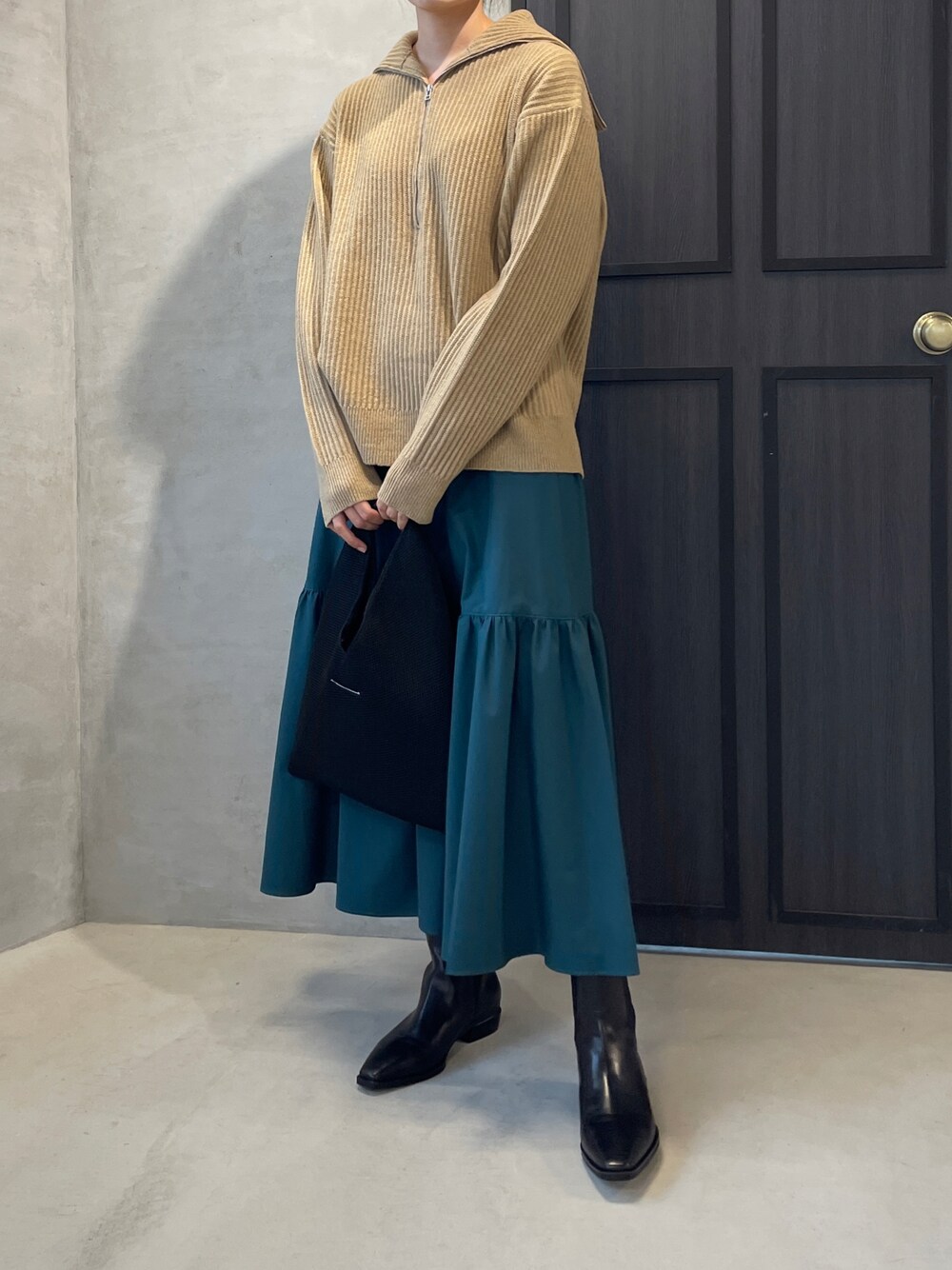 イエロー系のニット/セーター、グリーン系のスカートを着用したレディースの秋コーディネートの1枚目の写真