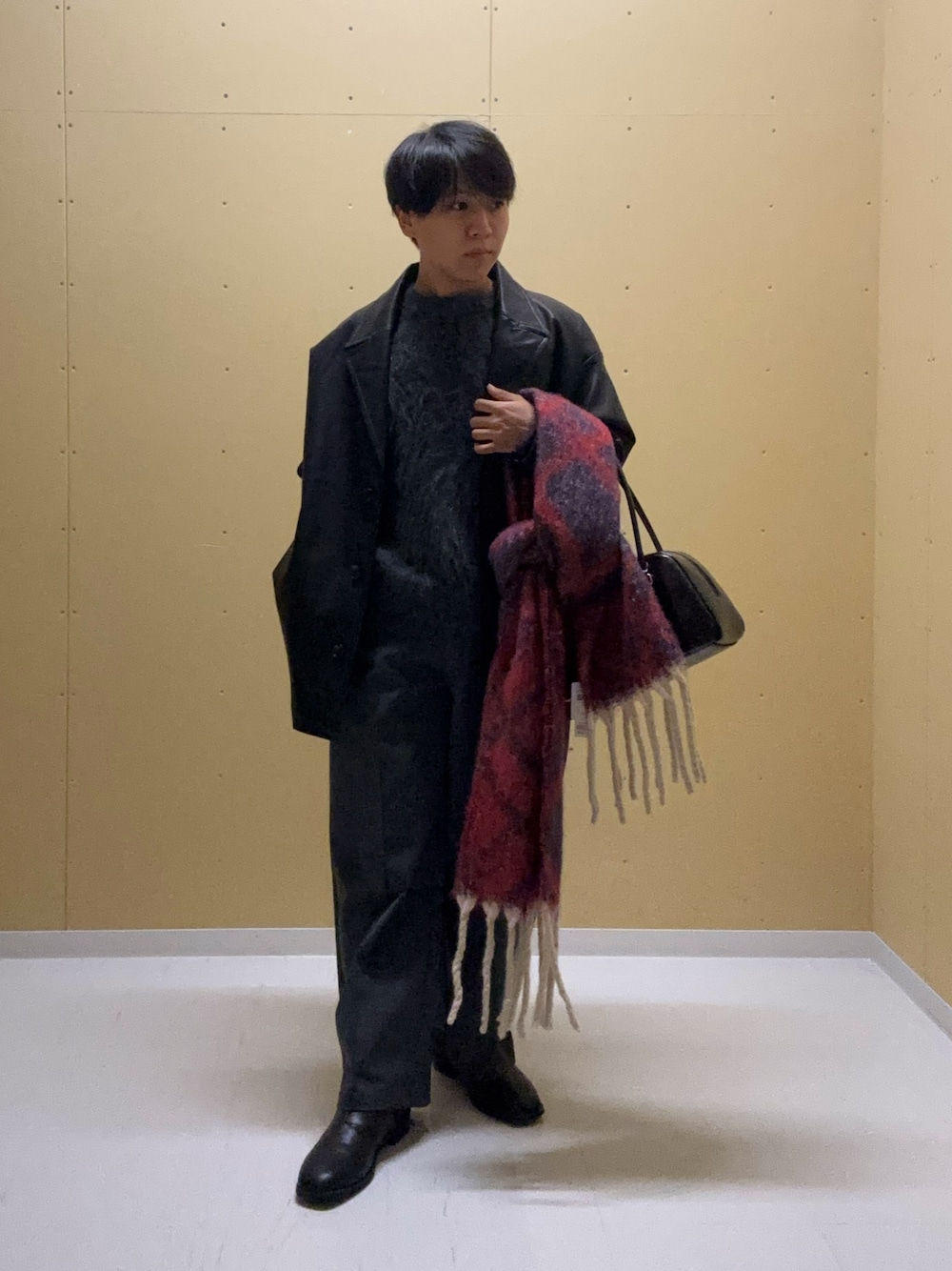 ブラック系のその他アウター、グレー系のニット/セーター、グレー系のスラックスを着用したメンズの秋コーディネートの1枚目の写真