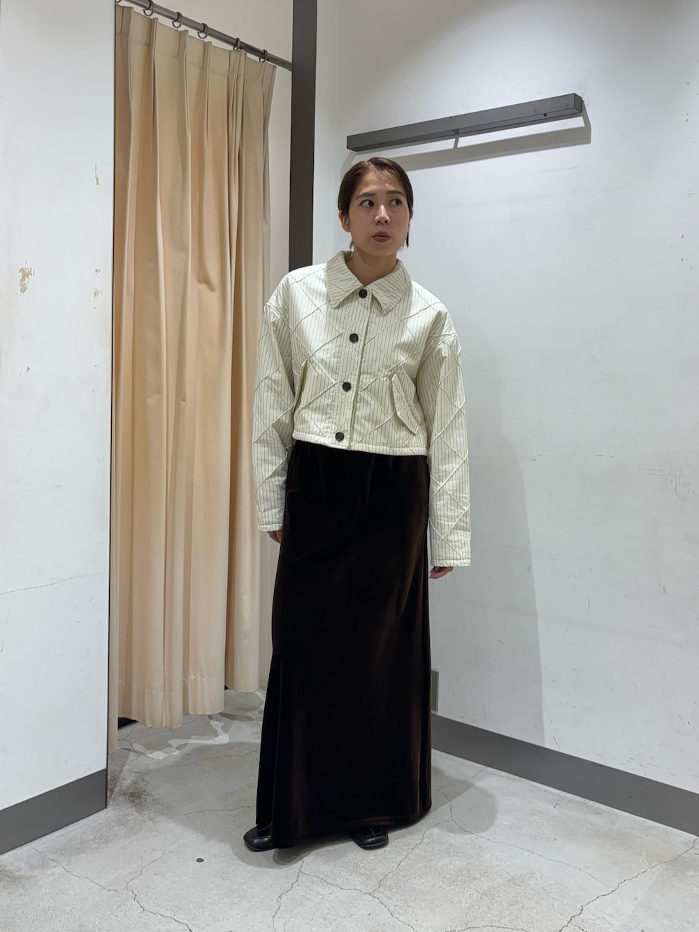 ブラウン系のスカート、ホワイト系のダウンジャケット/コートを着用したレディースの秋コーディネートの1枚目の写真