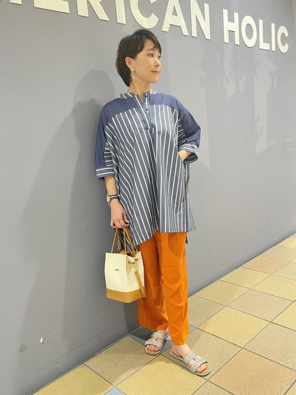 「ポンチョシャツ、シャツチュニック、ストライプシャツチュニック、ストライプシャツ、カラーパンツコーデ、カラーパンツ、センタープレスパンツ、接触冷感パンツ、カラーパンツ　オレンジ、オフィスカジュアル、アメリカンホリック、AMERICAN HOLIC、ハンサムコーデ、ワイドパンツコーデ」｜「AMERICAN HOLICの2Wayロゴキャンバスショルダーバッグ（ショルダーバッグ、ベージュ系）」を使った、ah.susuyuさん（骨格ストレート・レディース・158cm）の春コーディネートの1枚目の写真