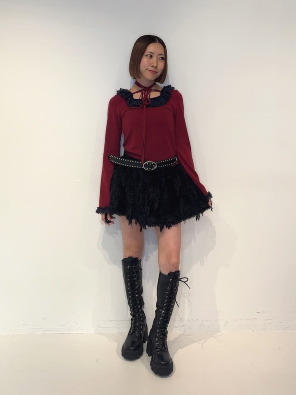 ブラック系のブーツ、ブラック系のスカート、レッド系のニット/セーターを着用したレディースの秋コーディネートの1枚目の写真