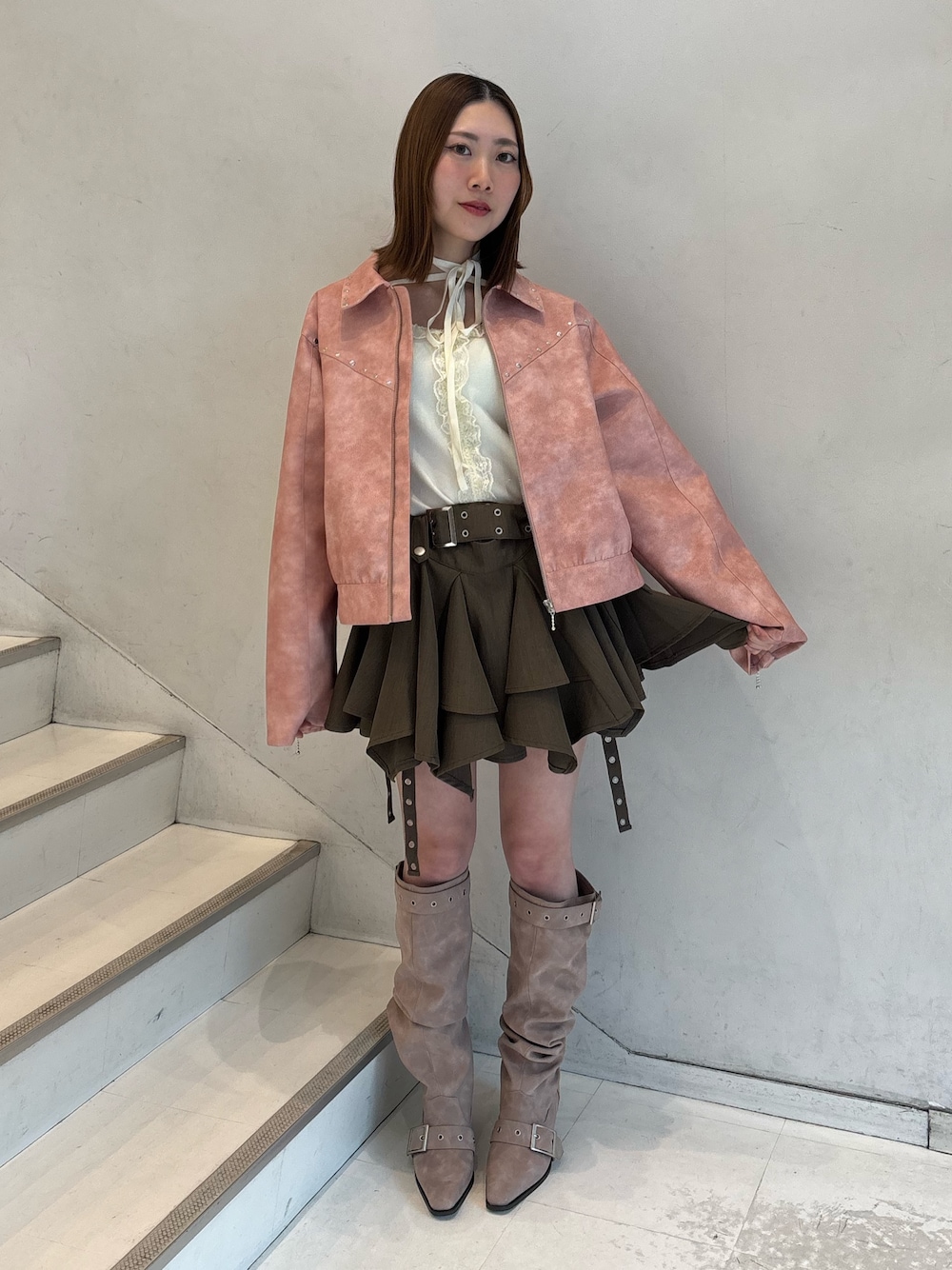 ベージュ系のスカート、ピンク系のブーツ、ピンク系のブルゾンを着用したレディースの冬コーディネートの1枚目の写真