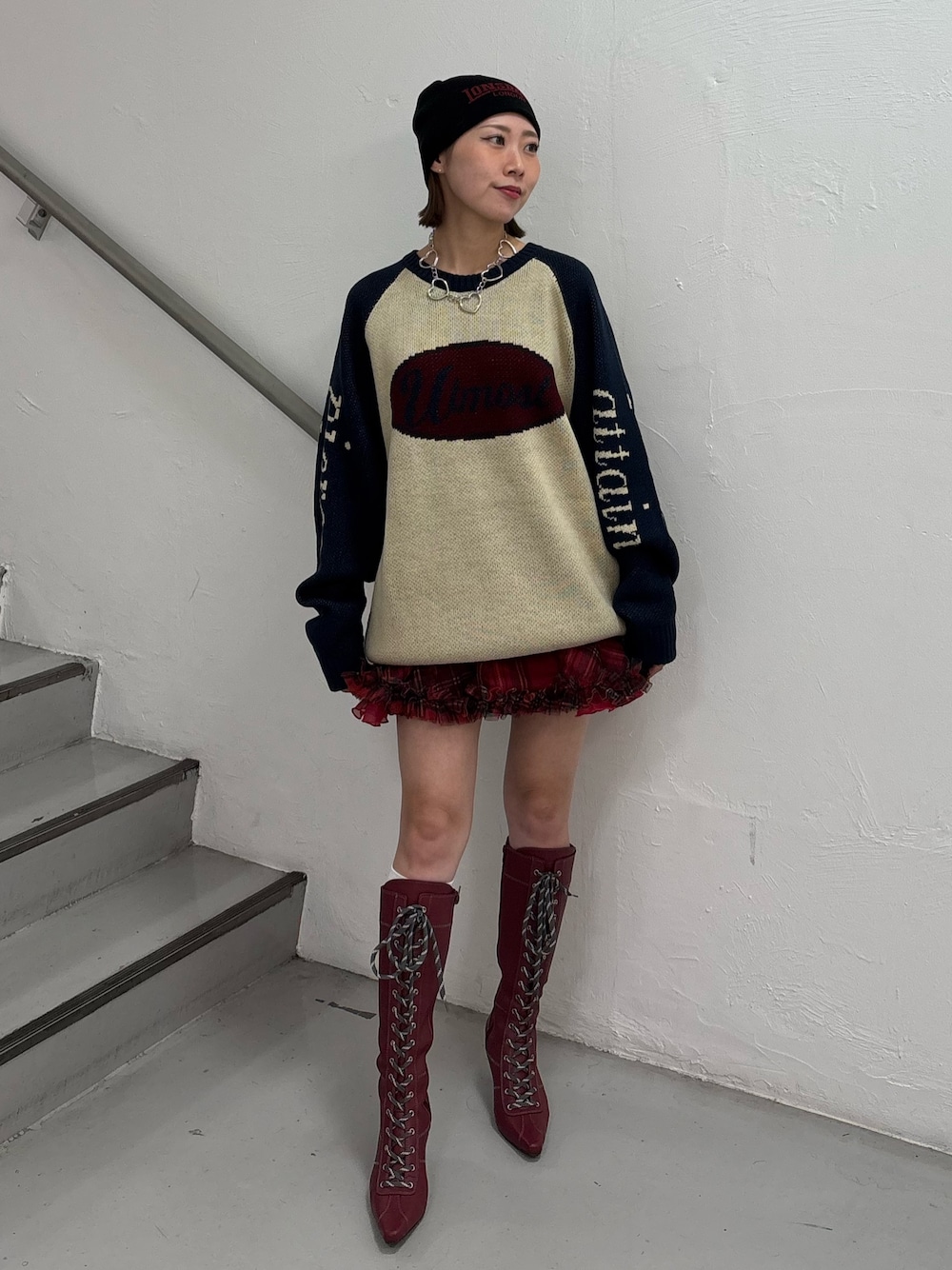 レッド系のブーツ、レッド系のスカート、ホワイト系のニット/セーターを着用したレディースの秋コーディネートの1枚目の写真