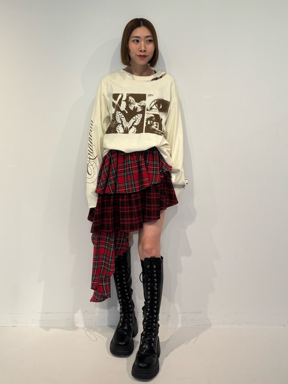 ブラック系のブーツ、ホワイト系のTシャツ/カットソー、レッド系のスカートを着用したレディースの冬コーディネートの1枚目の写真