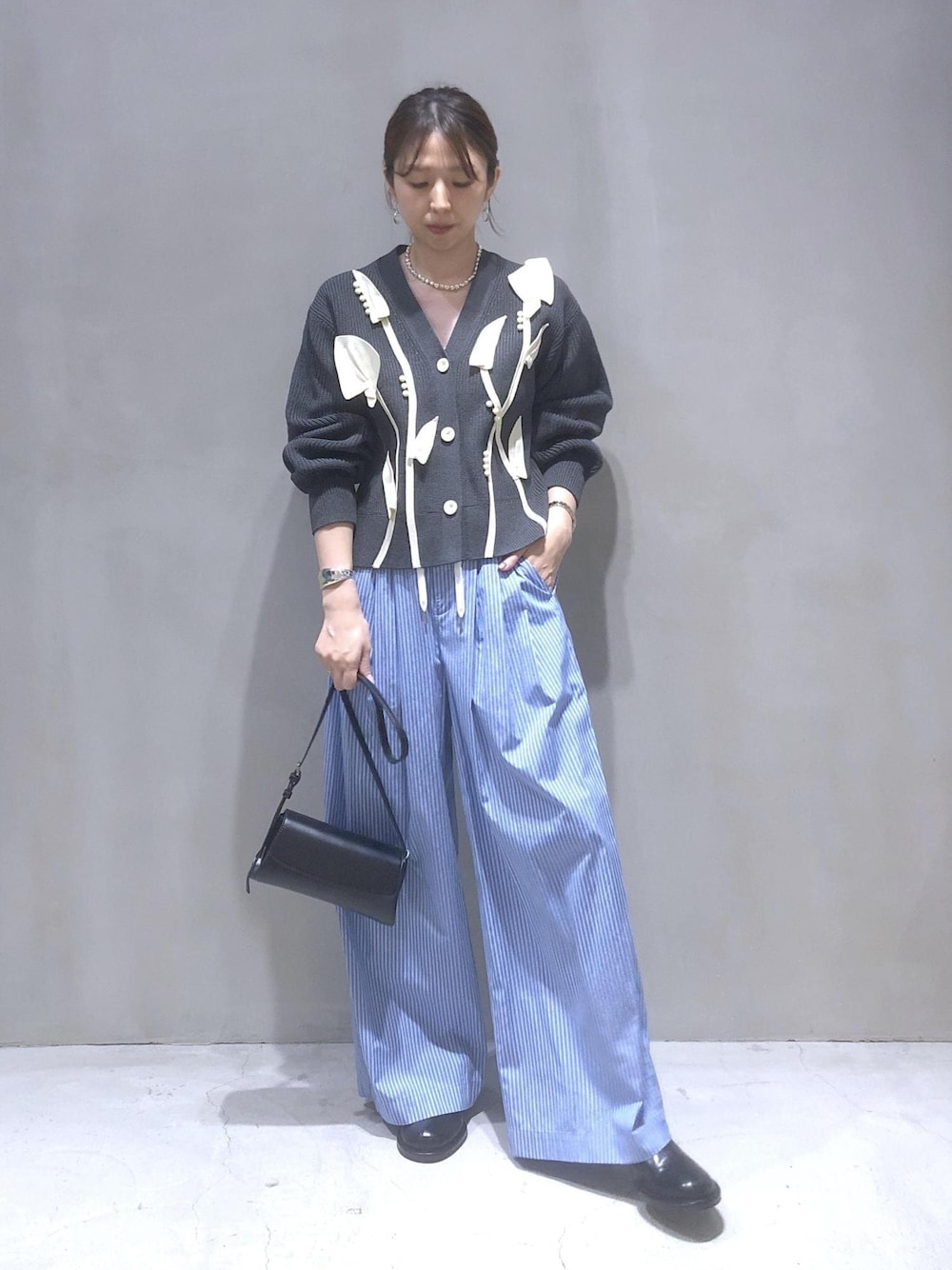 ブラック系のサンダル、グレー系のカーディガン/ボレロ、ブルー系のスラックスを着用したレディースの秋コーディネートの1枚目の写真