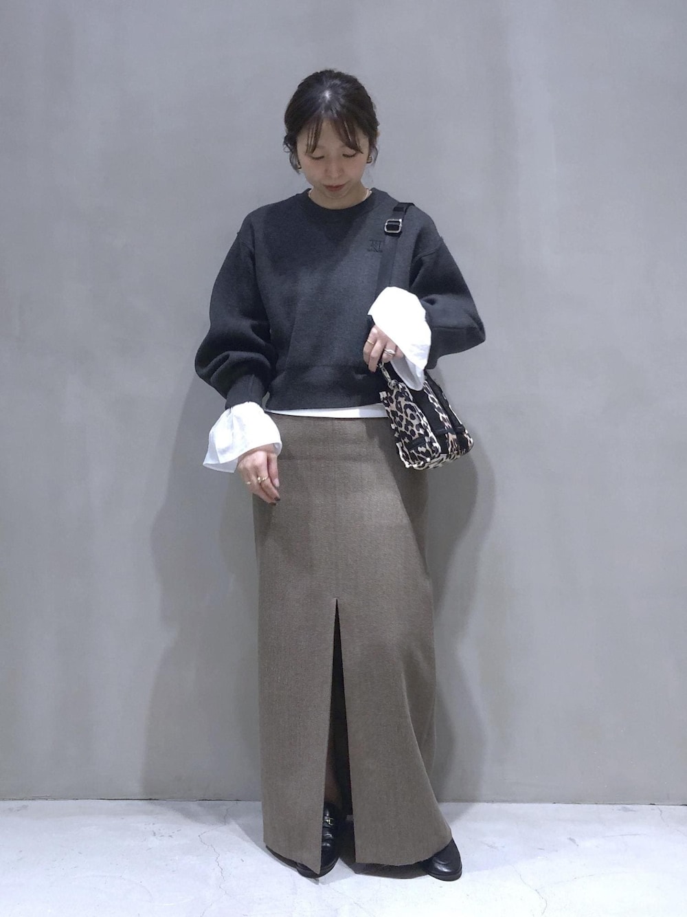 ベージュ系のスカート、グレー系のニット/セーターを着用したレディースの秋コーディネートの1枚目の写真