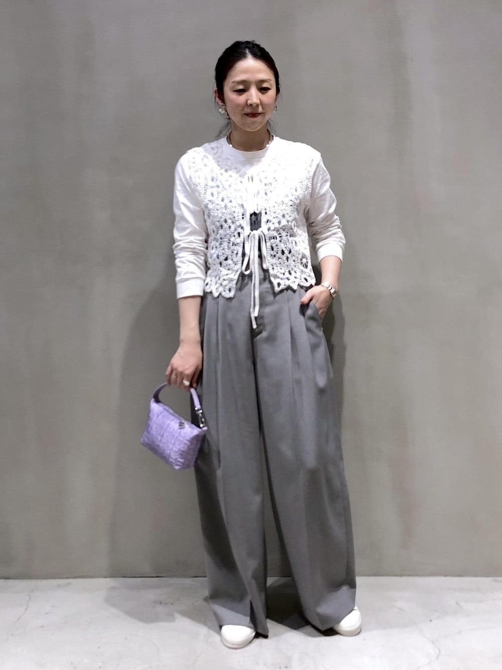 ホワイト系のベスト、パープル系のハンドバッグ、グレー系のスラックスを着用したレディースの冬コーディネートの1枚目の写真