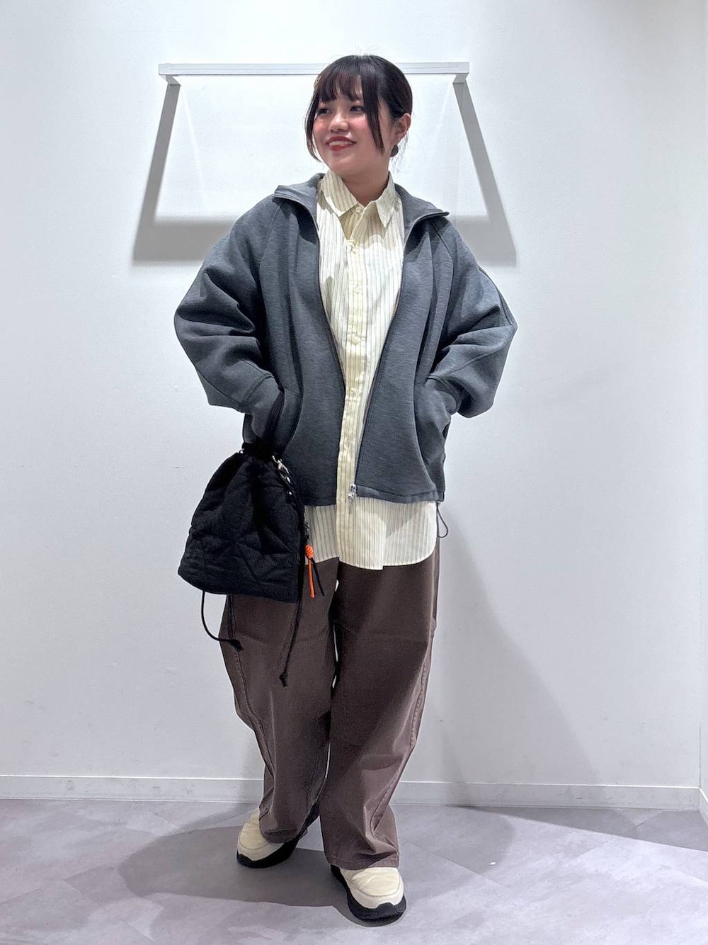 ブラック系のハンドバッグ、ブラウン系のデニムパンツ、ベージュ系のその他シューズを着用したレディースの春コーディネートの1枚目の写真