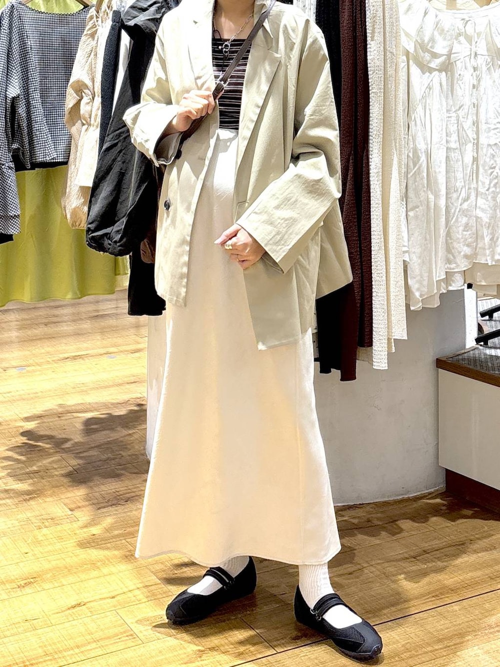 ホワイト系のスカート、ブラック系のスニーカー、ブラウン系のタンクトップを着用したレディースの春コーディネートの1枚目の写真