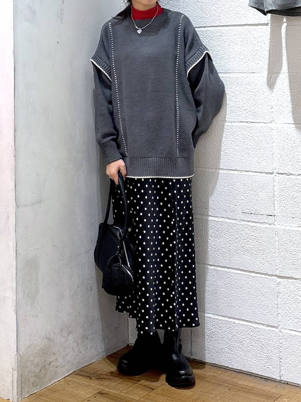 ブラック系のブーツ、ブラック系のスカート、グレー系のニット/セーターを着用したレディースの冬コーディネートの1枚目の写真