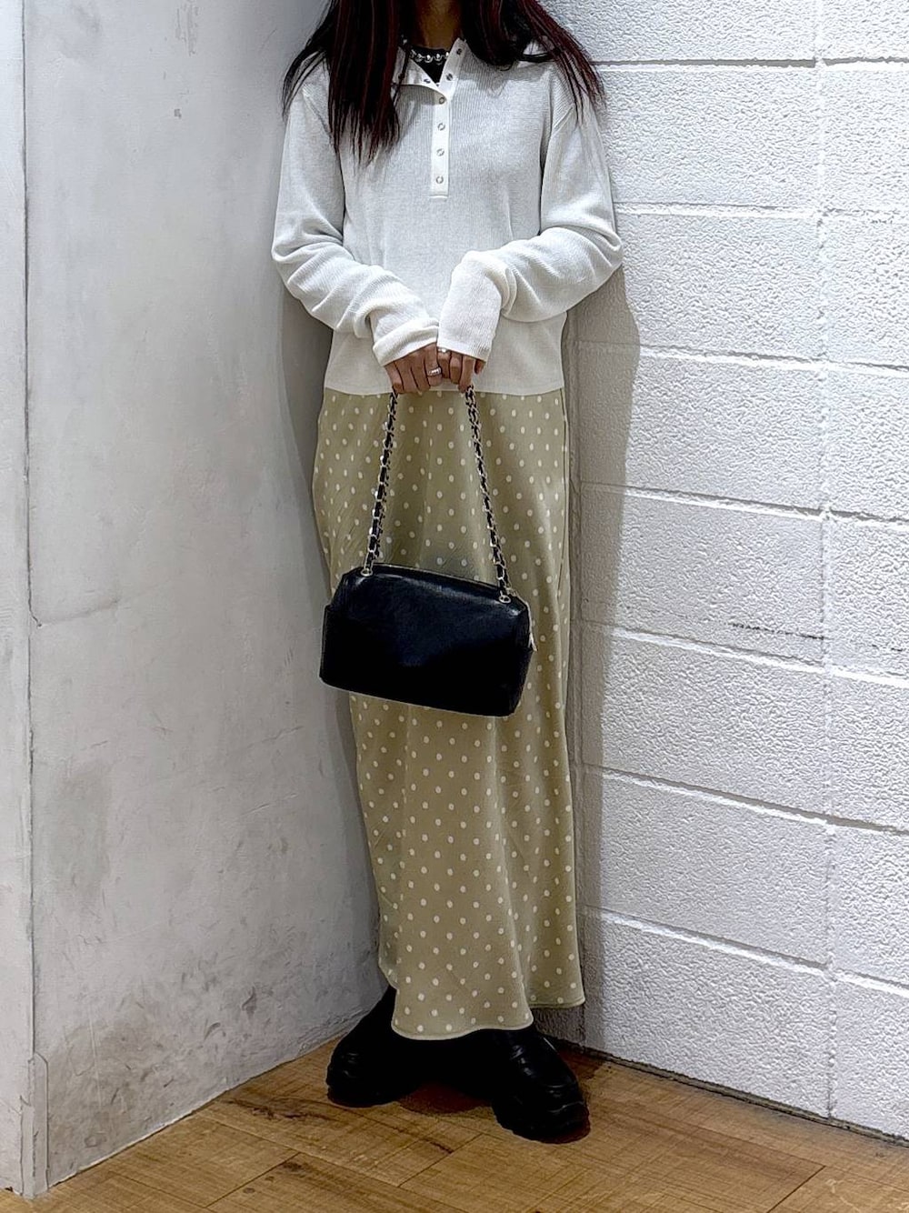 ベージュ系のスカート、ブラック系のニット/セーター、ホワイト系のニット/セーターを着用したレディースの冬コーディネートの1枚目の写真