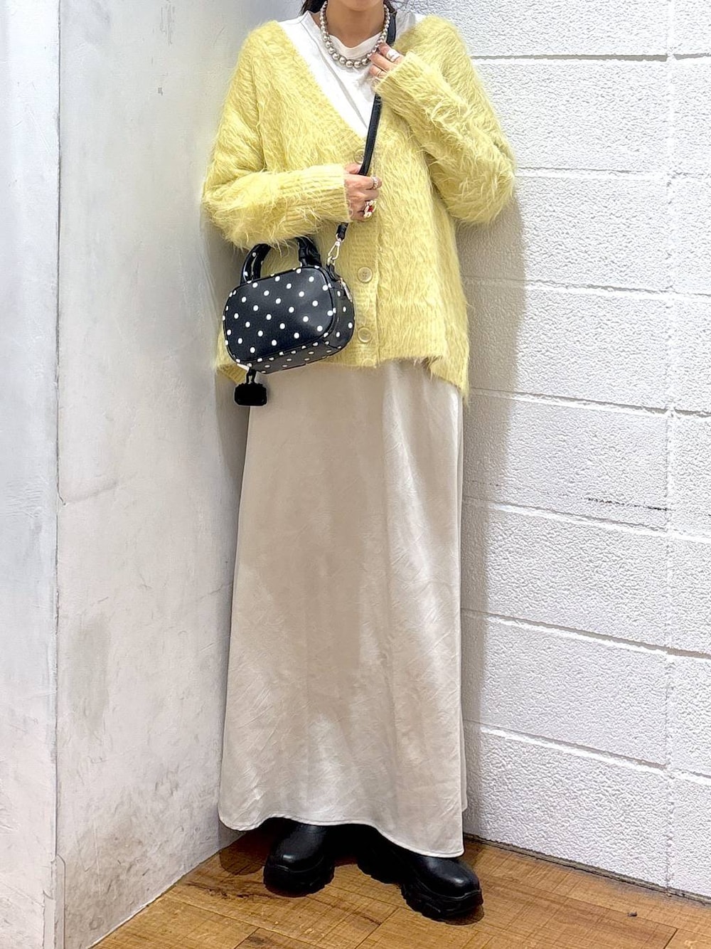 ブラック系のブーツ、ホワイト系のスカート、その他のボストンバッグを着用したレディースの秋コーディネートの1枚目の写真