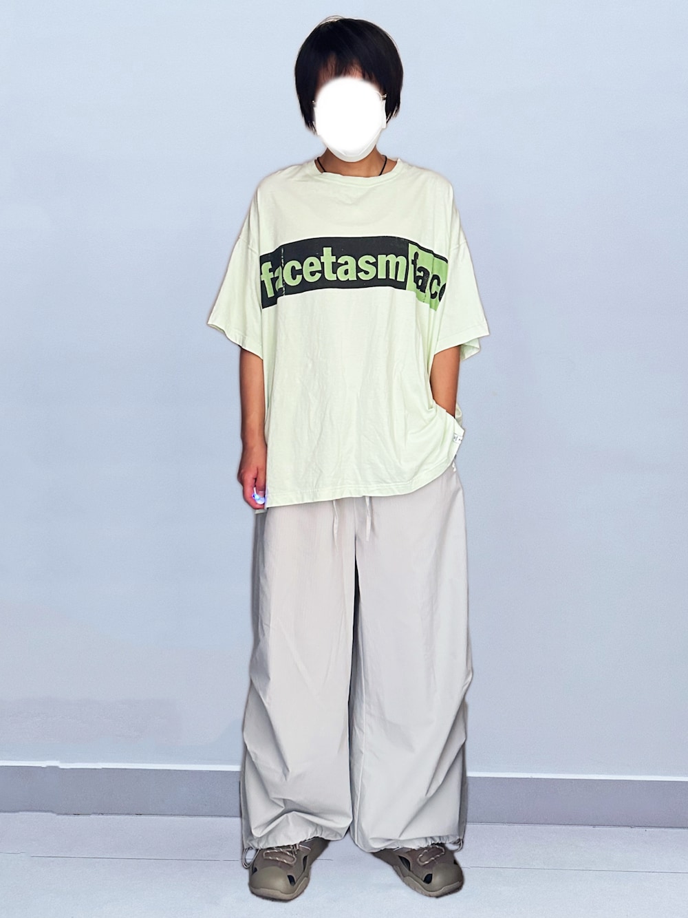 グリーン系のTシャツ/カットソー、グレー系のパンツ、グリーン系のサンダルを着用したレディースの秋コーディネートの1枚目の写真