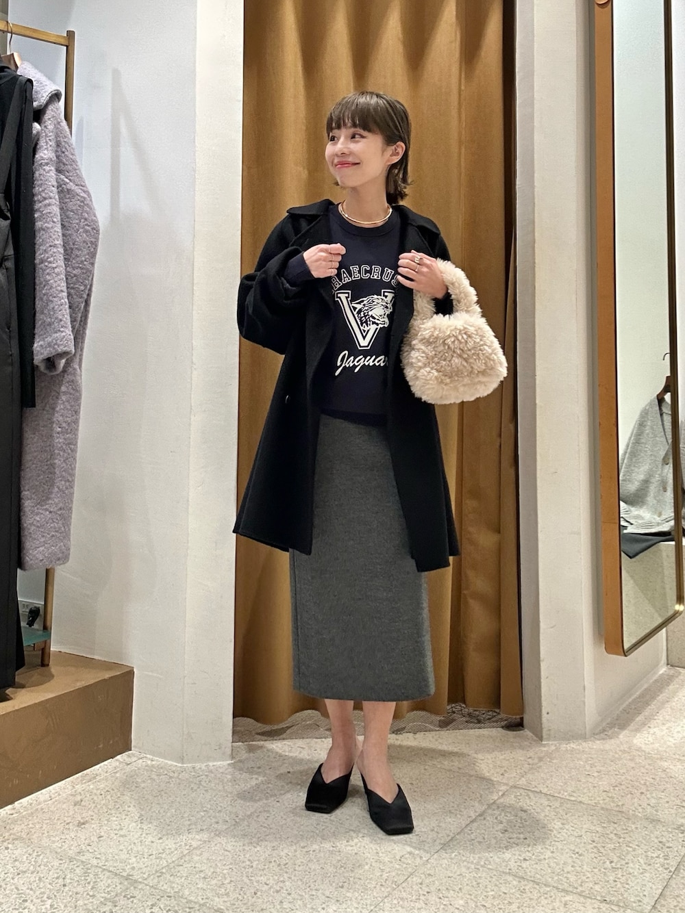 グレー系のスカート、ブルー系のスウェット、ブラック系のピーコートを着用したレディースの秋コーディネートの1枚目の写真