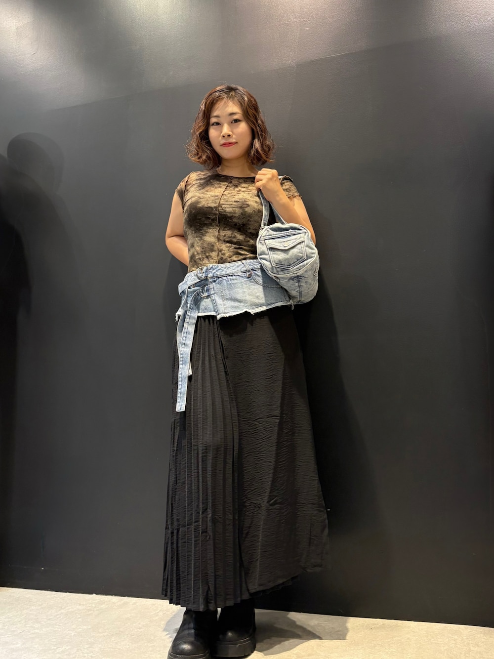 ブルー系のデニムスカート、ブラック系のTシャツ/カットソー、ブルー系のハンドバッグを着用したレディースの夏コーディネートの1枚目の写真