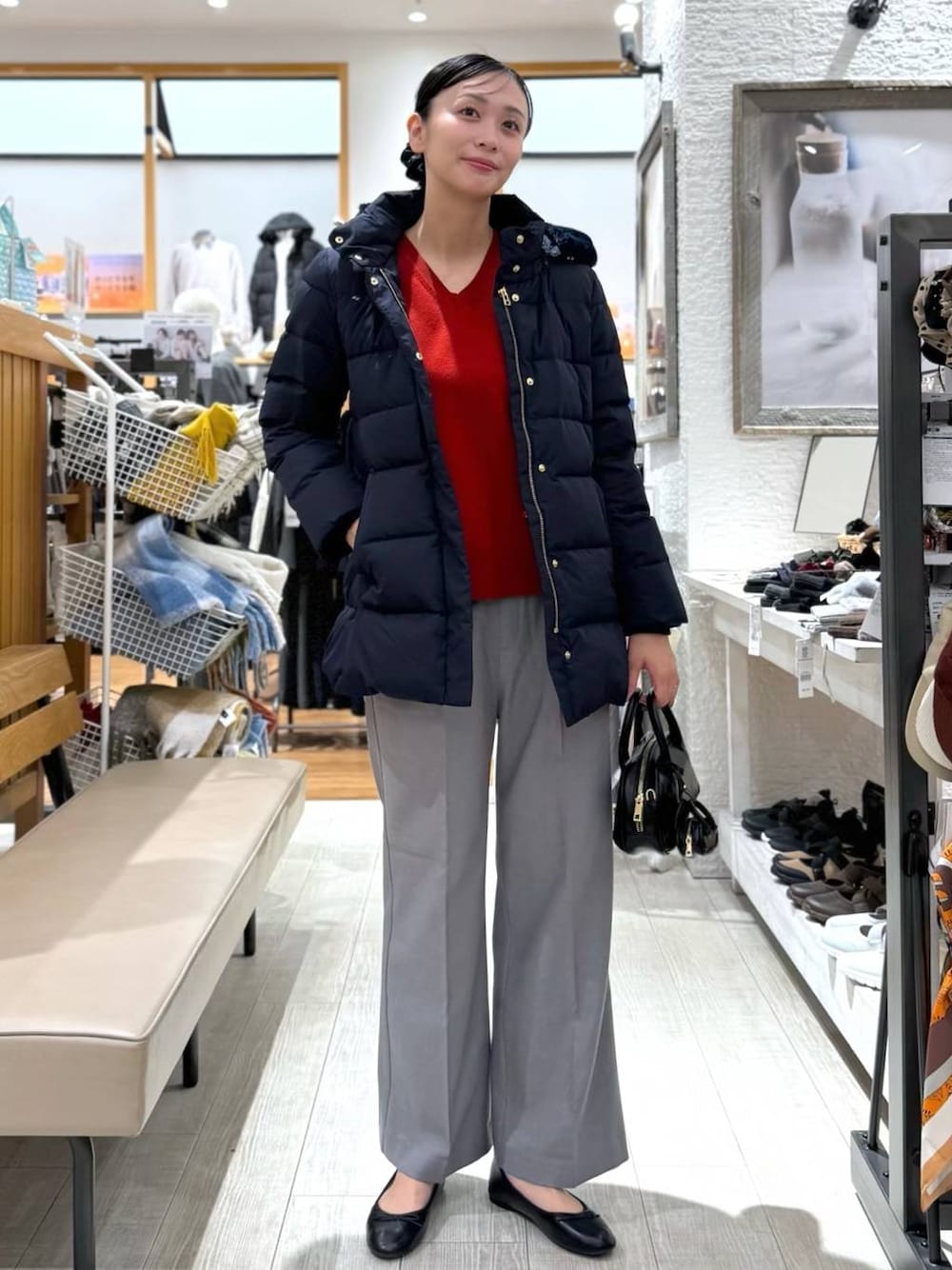 ブラック系のバレエシューズ、ブルー系のダウンジャケット/コート、レッド系のニット/セーターを着用したレディースの秋コーディネートの1枚目の写真