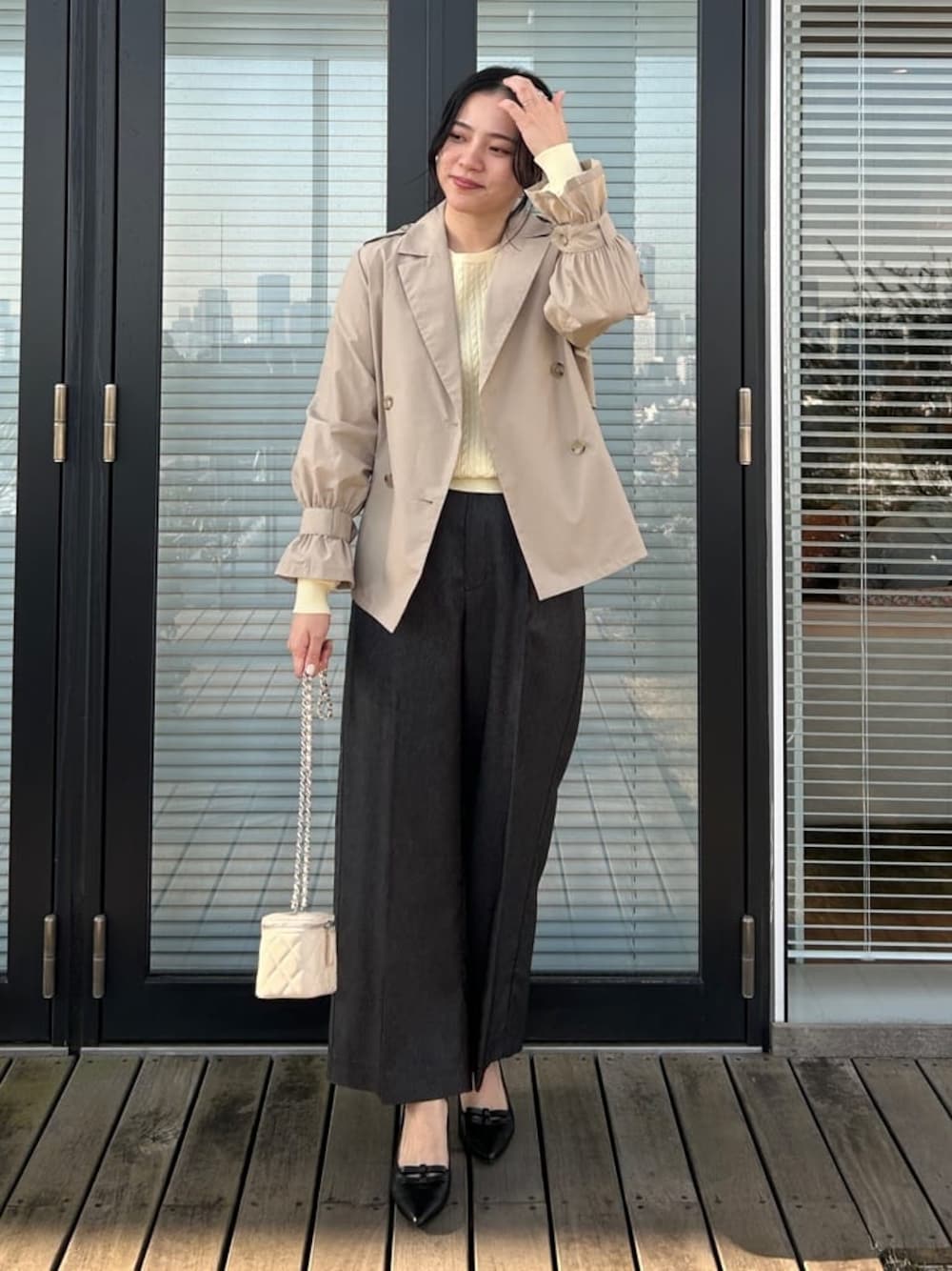 ベージュ系のトレンチコート、イエロー系のニット/セーター、ブラック系のその他パンツを着用したレディースの春コーディネートの1枚目の写真