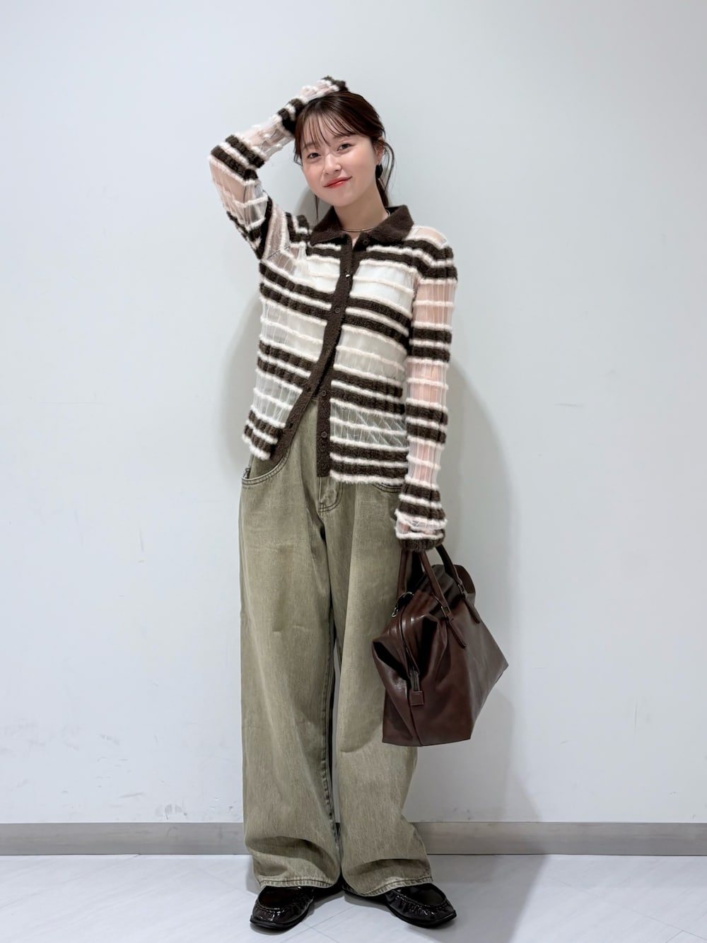 ブラウン系のニット/セーター、グリーン系のデニムパンツ、ブラウン系のボストンバッグを着用したレディースの秋コーディネートの1枚目の写真