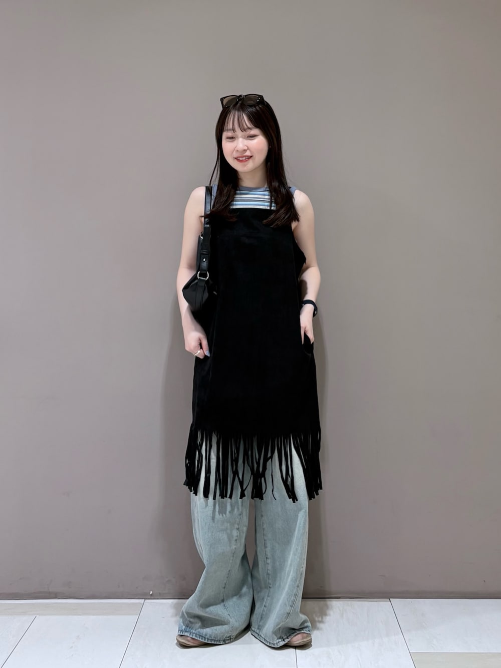 ブルー系のデニムパンツ、ブラック系のショルダーバッグ、ブルー系のタンクトップを着用したレディースの夏コーディネートの1枚目の写真