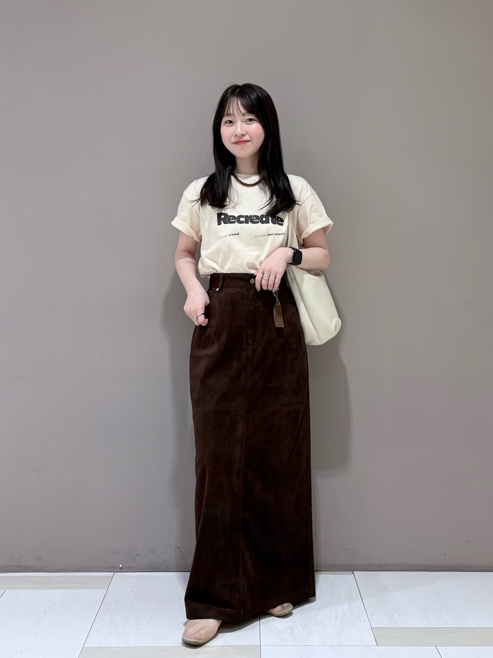 ブラウン系のスカート、ホワイト系のショルダーバッグ、ホワイト系のTシャツ/カットソーを着用したレディースの夏コーディネートの1枚目の写真
