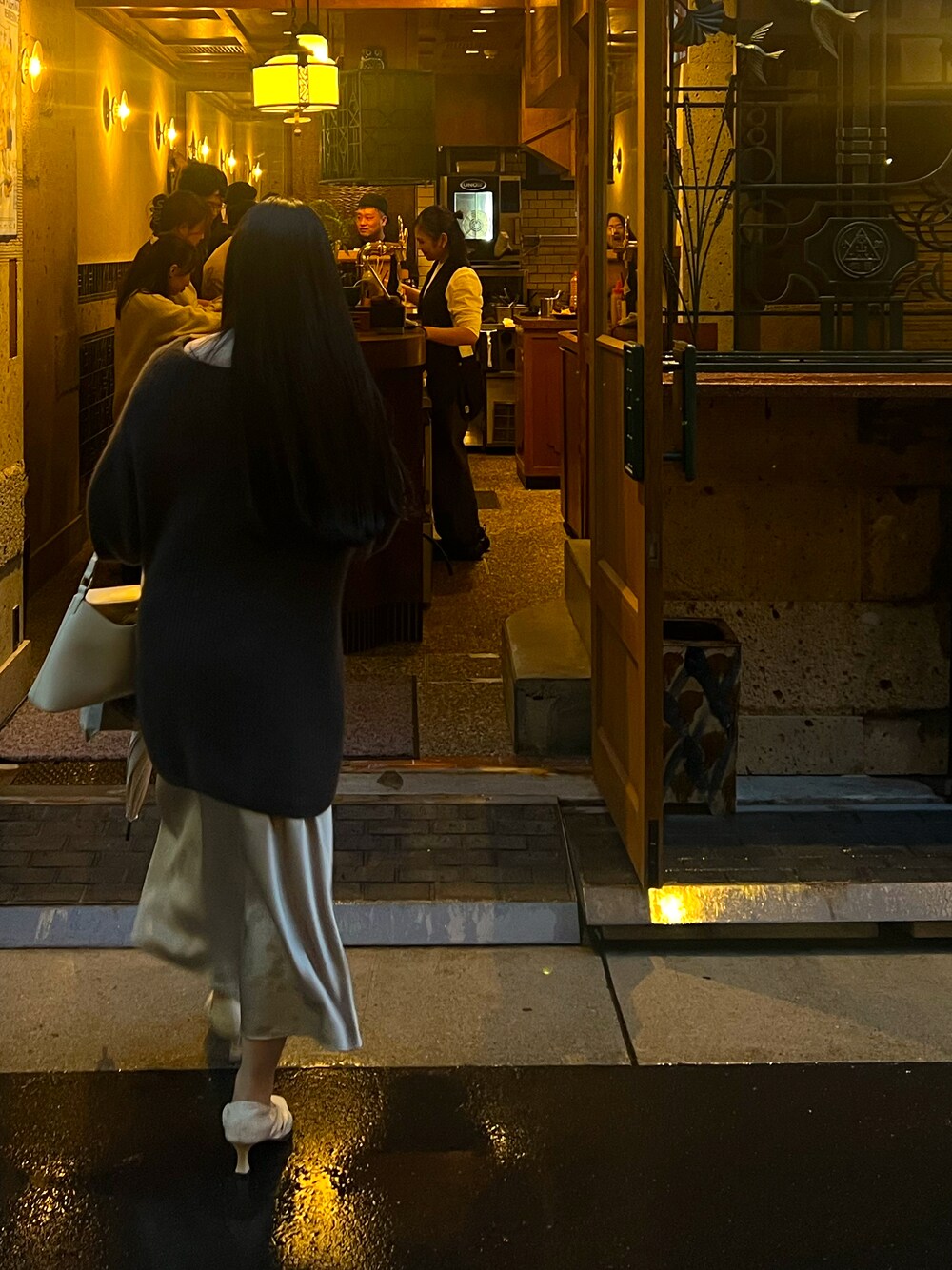 ベージュ系のスカート、ブラウン系のニット/セーター、ホワイト系のハンドバッグを着用したレディースの秋コーディネートの1枚目の写真