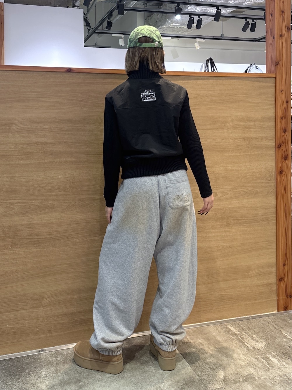 ブラック系のブルゾン、グレー系のスウェットパンツ、グリーン系のキャップを着用したレディースの冬コーディネートの1枚目の写真