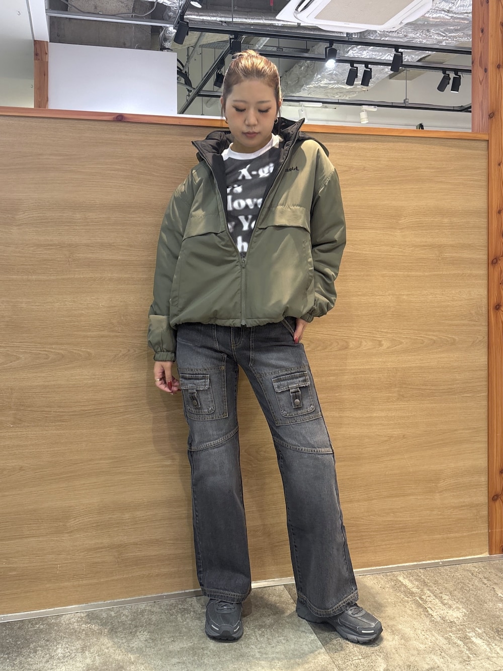 グリーン系のナイロンジャケット、ホワイト系のTシャツ/カットソー、ブラック系のデニムパンツを着用したレディースの秋コーディネートの1枚目の写真