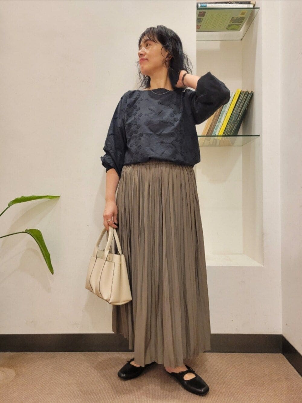 ベージュ系のスカート、ブラック系のシャツ/ブラウス、ブラック系のサンダルを着用したレディースの秋コーディネートの1枚目の写真