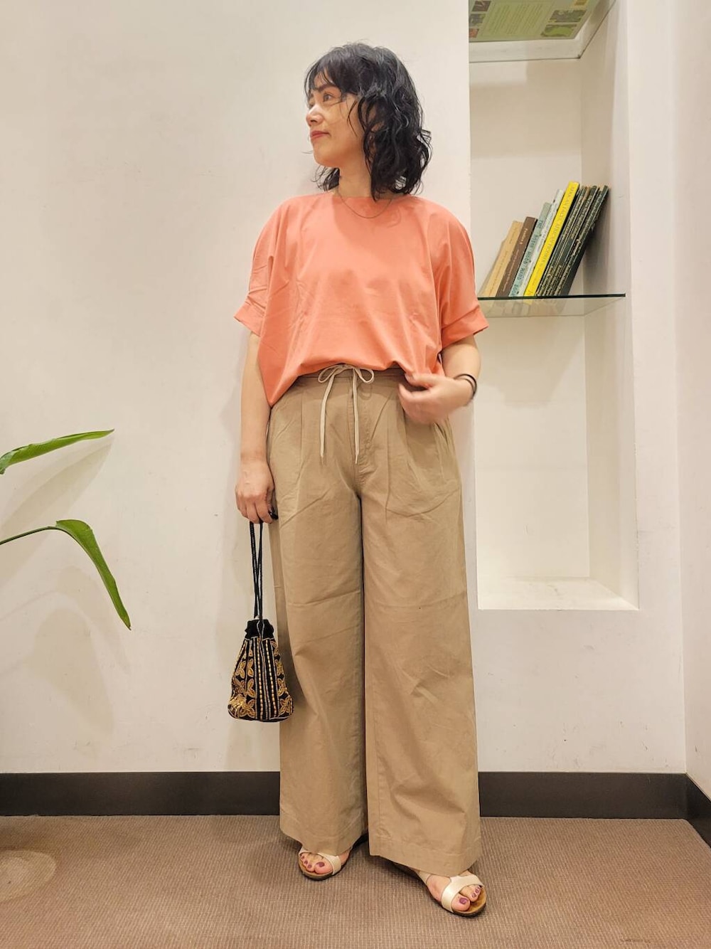 オレンジ系のTシャツ/カットソー、ブラック系のショルダーバッグ、ホワイト系のサンダルを着用したレディースの夏コーディネートの1枚目の写真