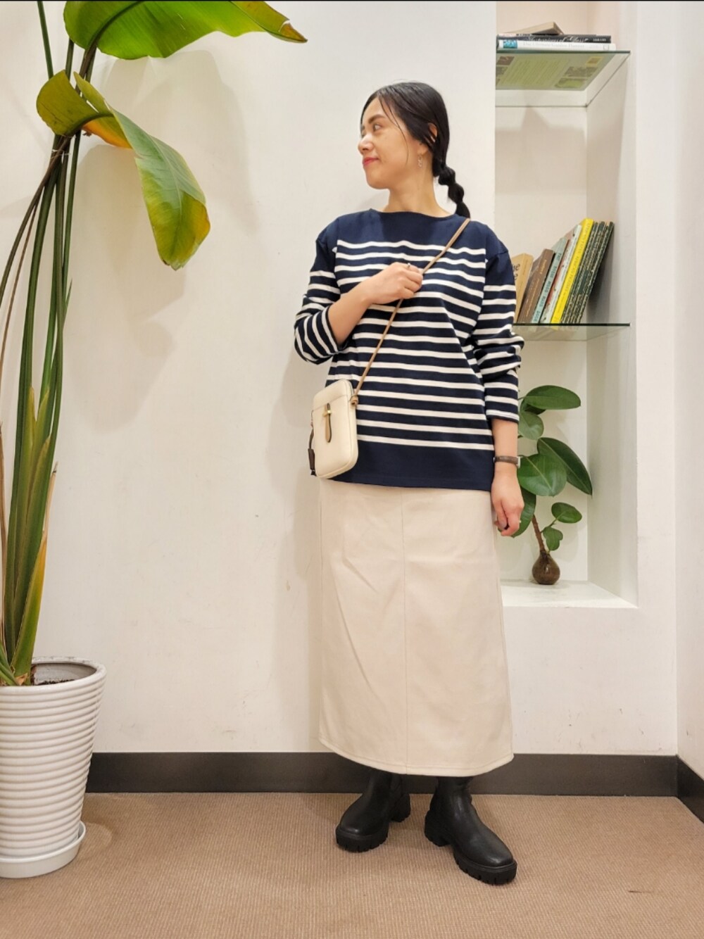 ホワイト系のショルダーバッグ、ブラック系のブーツ、ホワイト系のスカートを着用したレディースの秋コーディネートの1枚目の写真