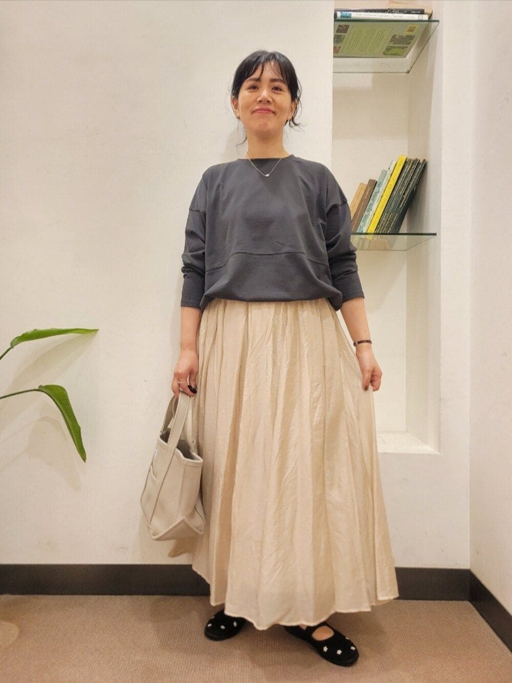グレー系のTシャツ/カットソー、ベージュ系のスカート、ブラック系のスニーカーを着用したレディースの秋コーディネートの1枚目の写真