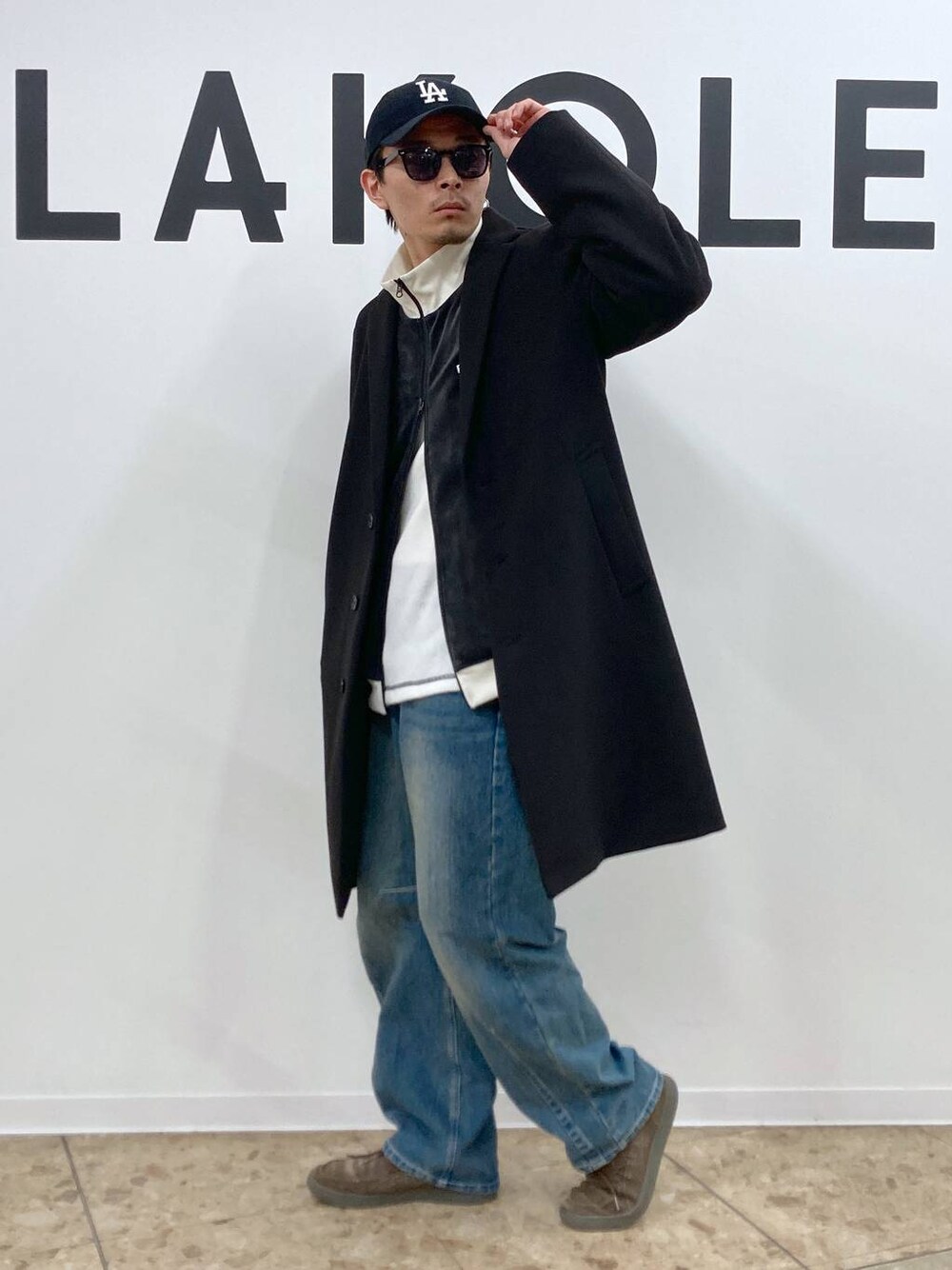 ブラック系のチェスターコート、ブルー系のデニムパンツ、ホワイト系のTシャツ/カットソーを着用したメンズの秋コーディネートの1枚目の写真