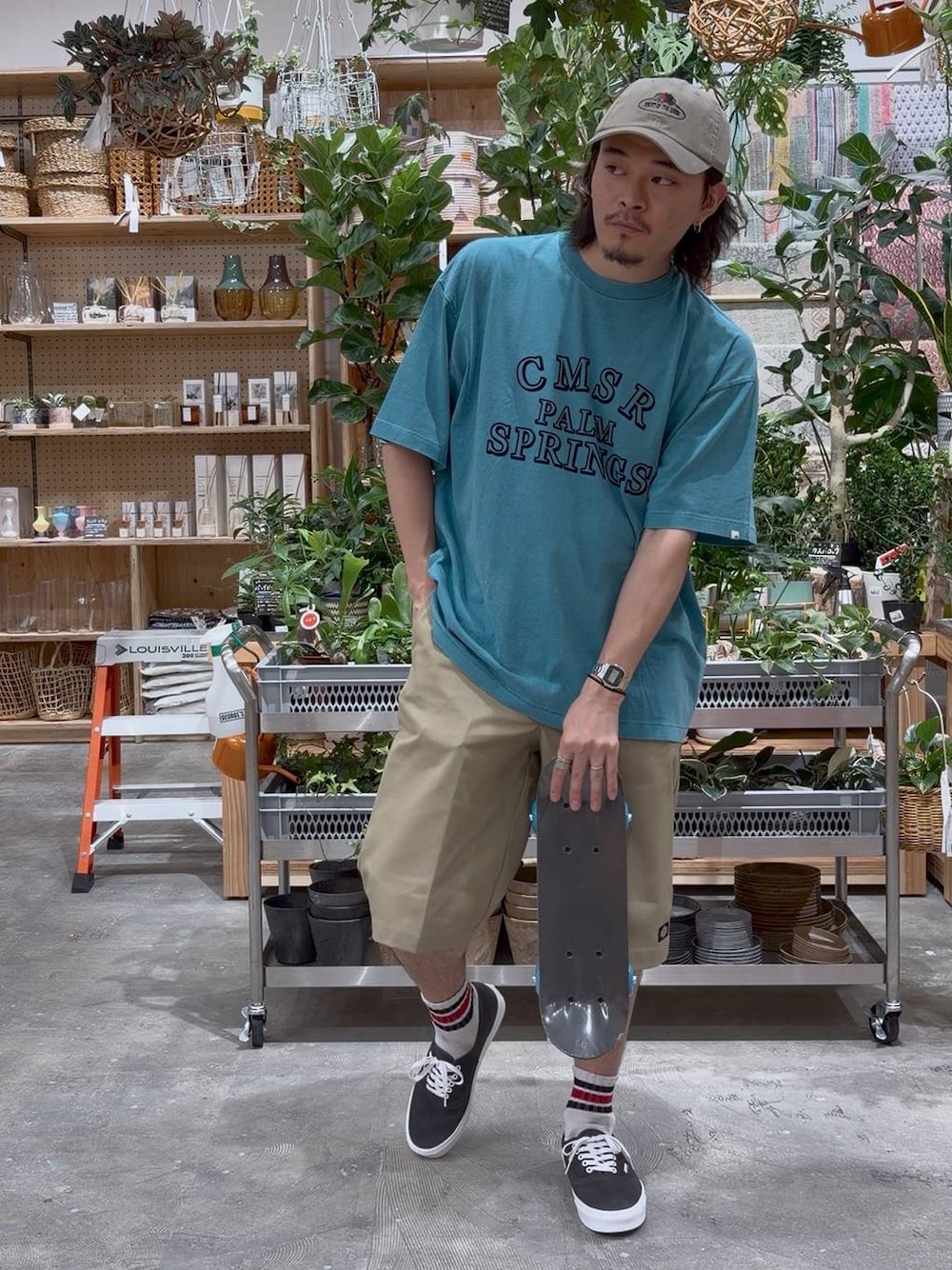 グリーン系のTシャツ/カットソー、ブルー系のスポーツグッズ、ベージュ系のキャップを着用したメンズの夏コーディネートの1枚目の写真
