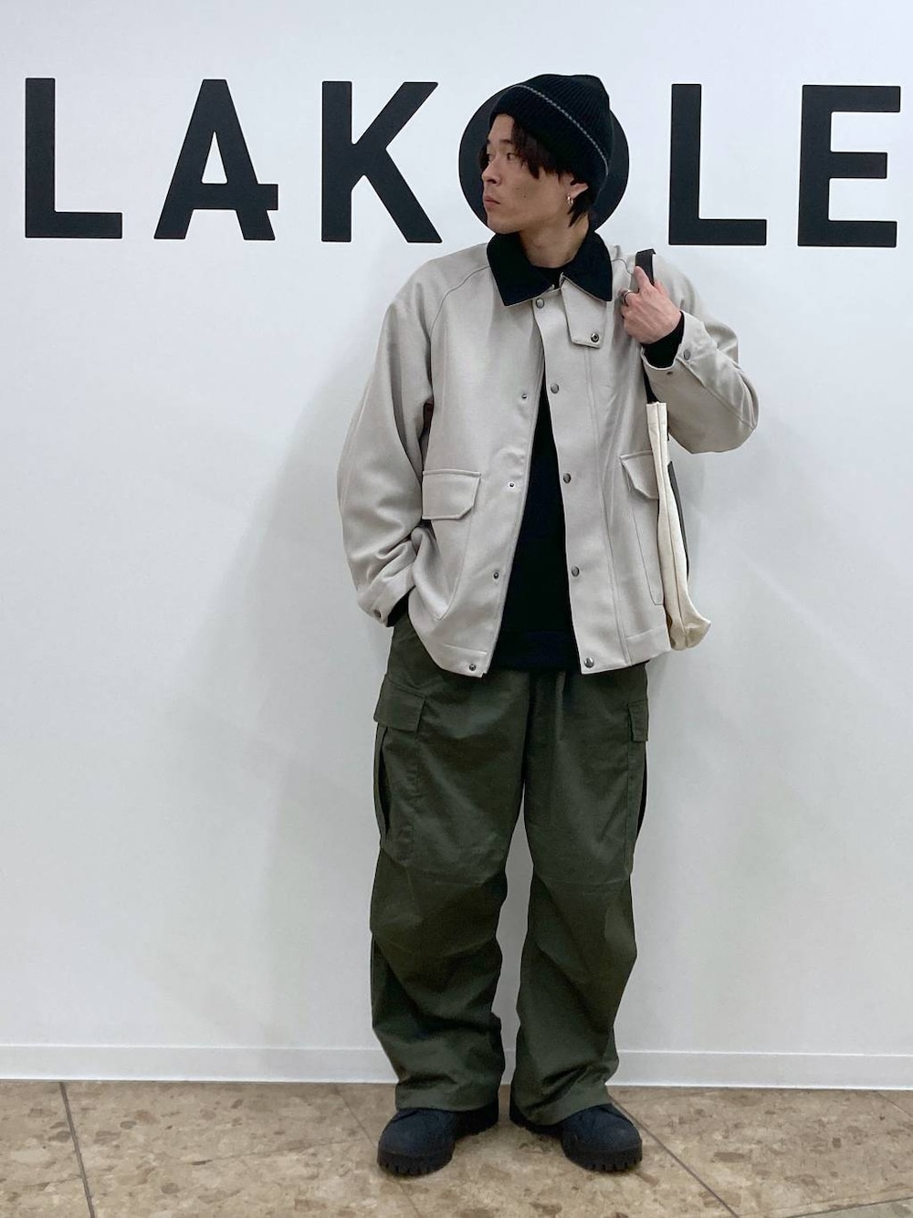 ベージュ系のトートバッグ、ブラック系のその他トップス、グリーン系のカーゴパンツを着用したメンズの冬コーディネートの1枚目の写真