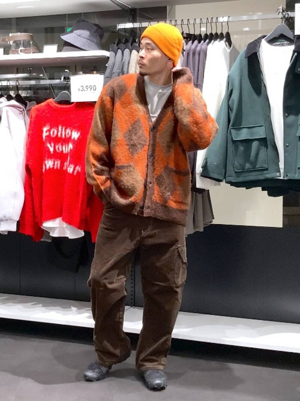 ブラウン系のその他パンツ、ブラウン系のカーディガン/ボレロ、オレンジ系のニットキャップ/ビーニーを着用したメンズの冬コーディネートの1枚目の写真