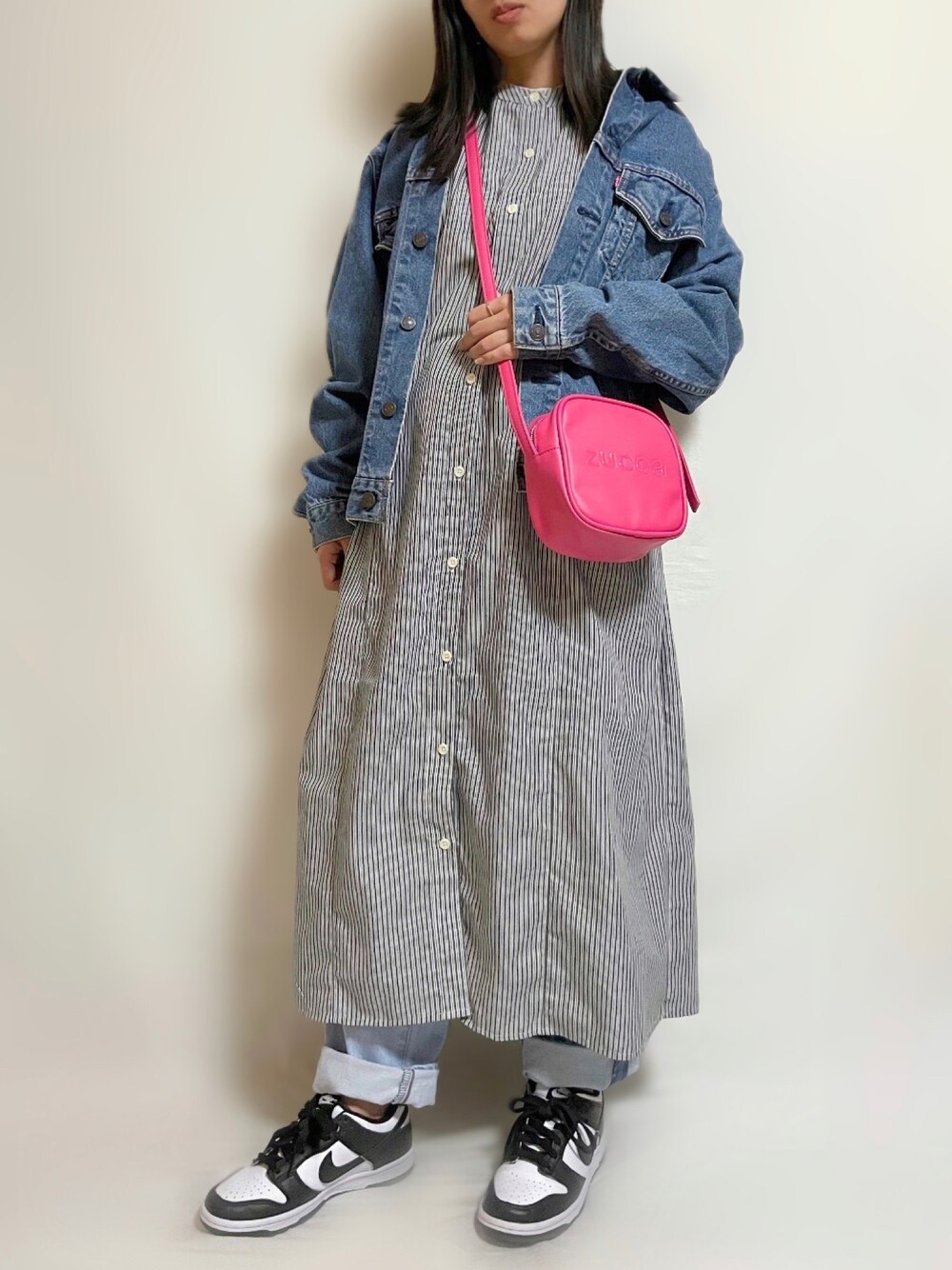 ブラック系のワンピース、ピンク系のショルダーバッグ、ブルー系のデニムジャケットを着用したレディースの春コーディネートの1枚目の写真