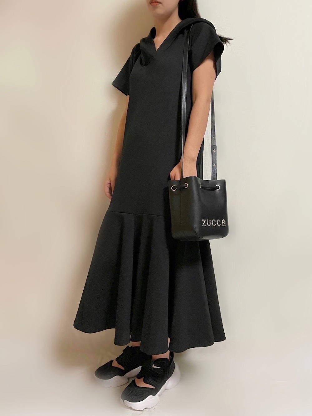 ブラック系のワンピース、ブラック系のショルダーバッグ、ブラック系のスニーカーを着用したレディースの春コーディネートの1枚目の写真