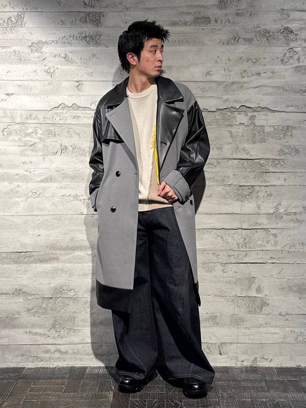 グレー系のトレンチコート、ブラック系のスニーカー、ホワイト系のニット/セーターを着用したメンズの秋コーディネートの1枚目の写真