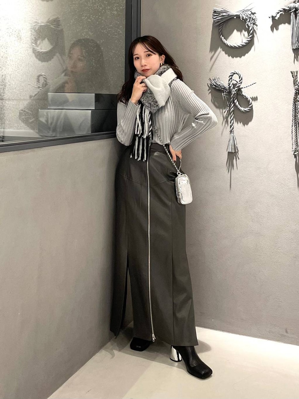 ホワイト系のニット/セーター、ブラック系のブーツ、グレー系のスカートを着用したレディースの冬コーディネートの1枚目の写真