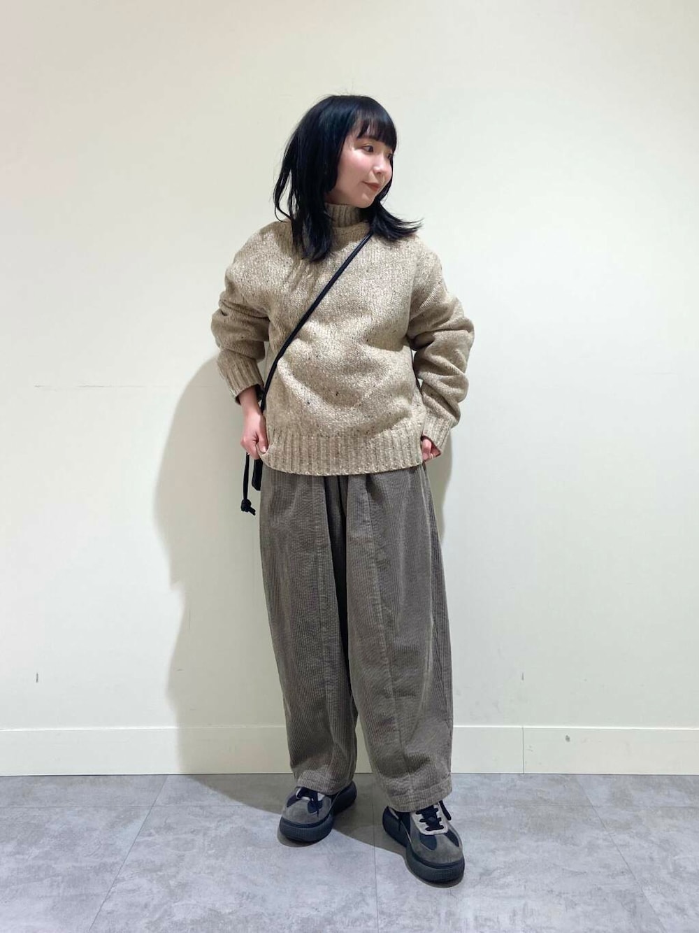 ベージュ系のニット/セーター、グレー系のその他パンツ、ブラック系のショルダーバッグを着用したレディースの冬コーディネートの1枚目の写真